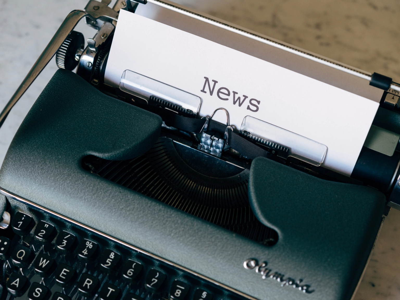 Symbolbild Presse: Schreibmaschine mit eingelegtem Blatt Papier auf dem News getippt steht.
